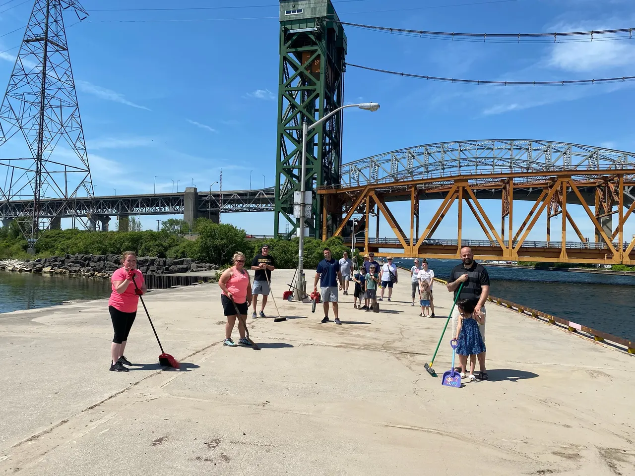Volunteers sweeping the Hamilton-Burlington canal piers with the lift bridge behind them