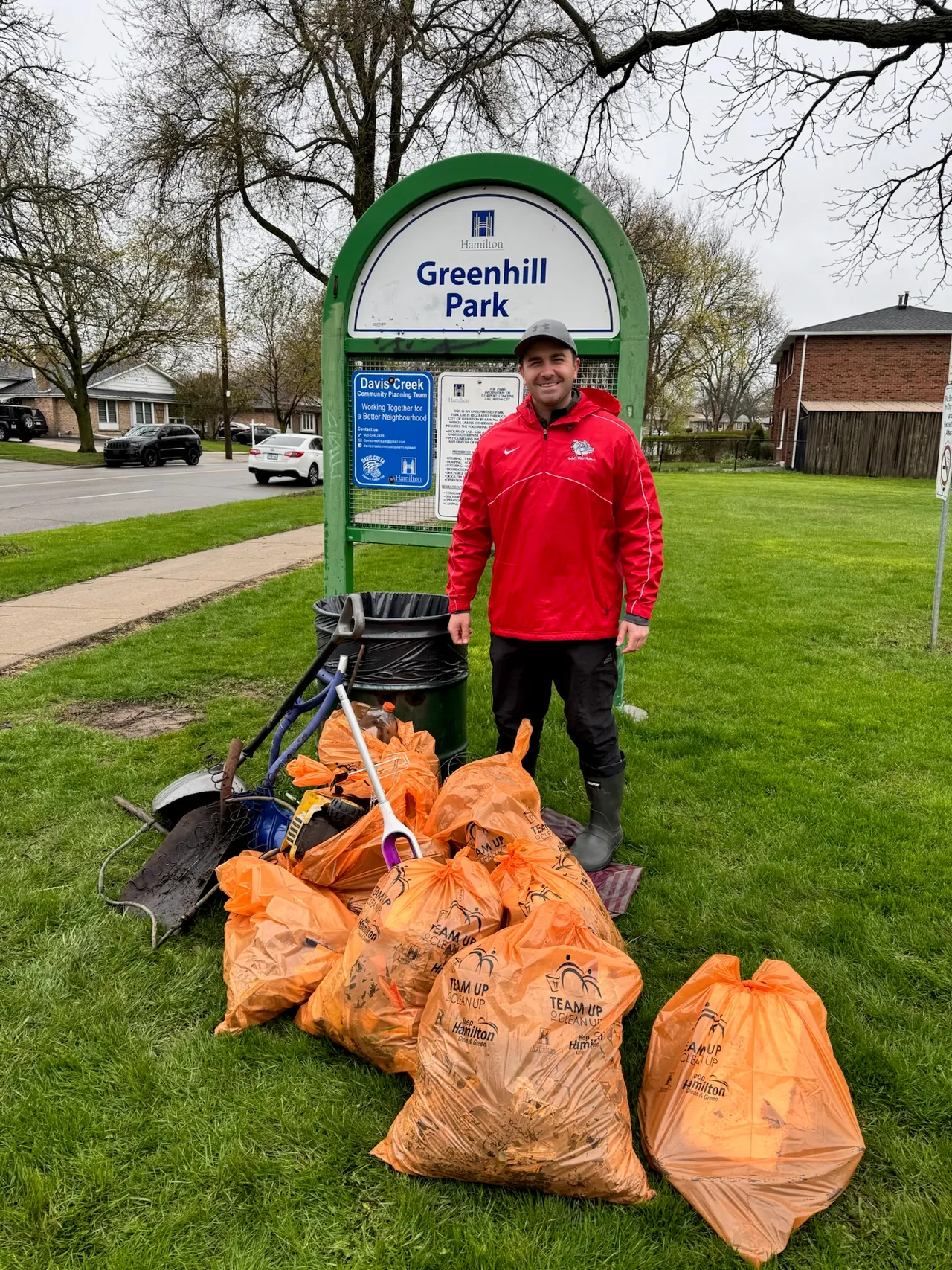 Bags of collected litter beside the Greenhill Park sign after a community cleanup