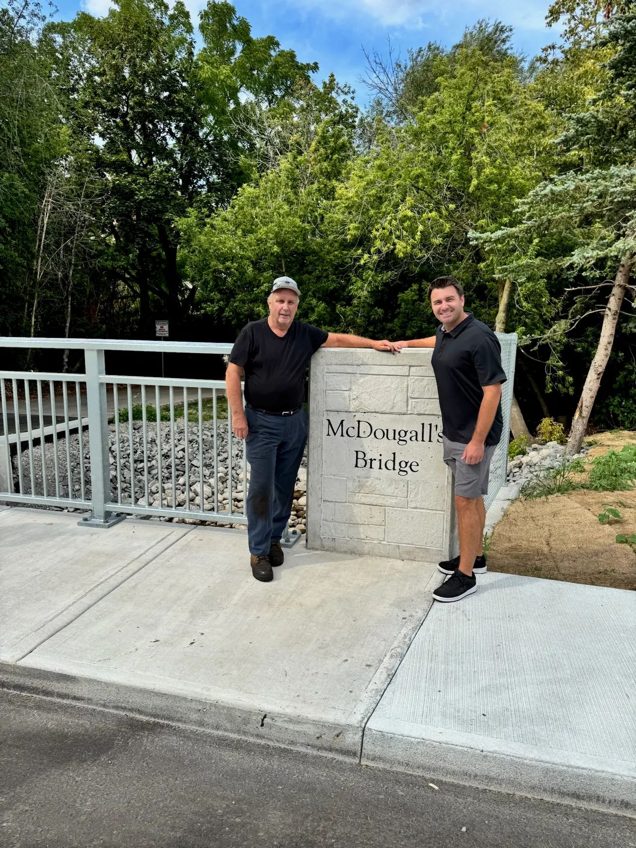 Matt Francis beside the sign for the newly renamed McDougall's Bridge