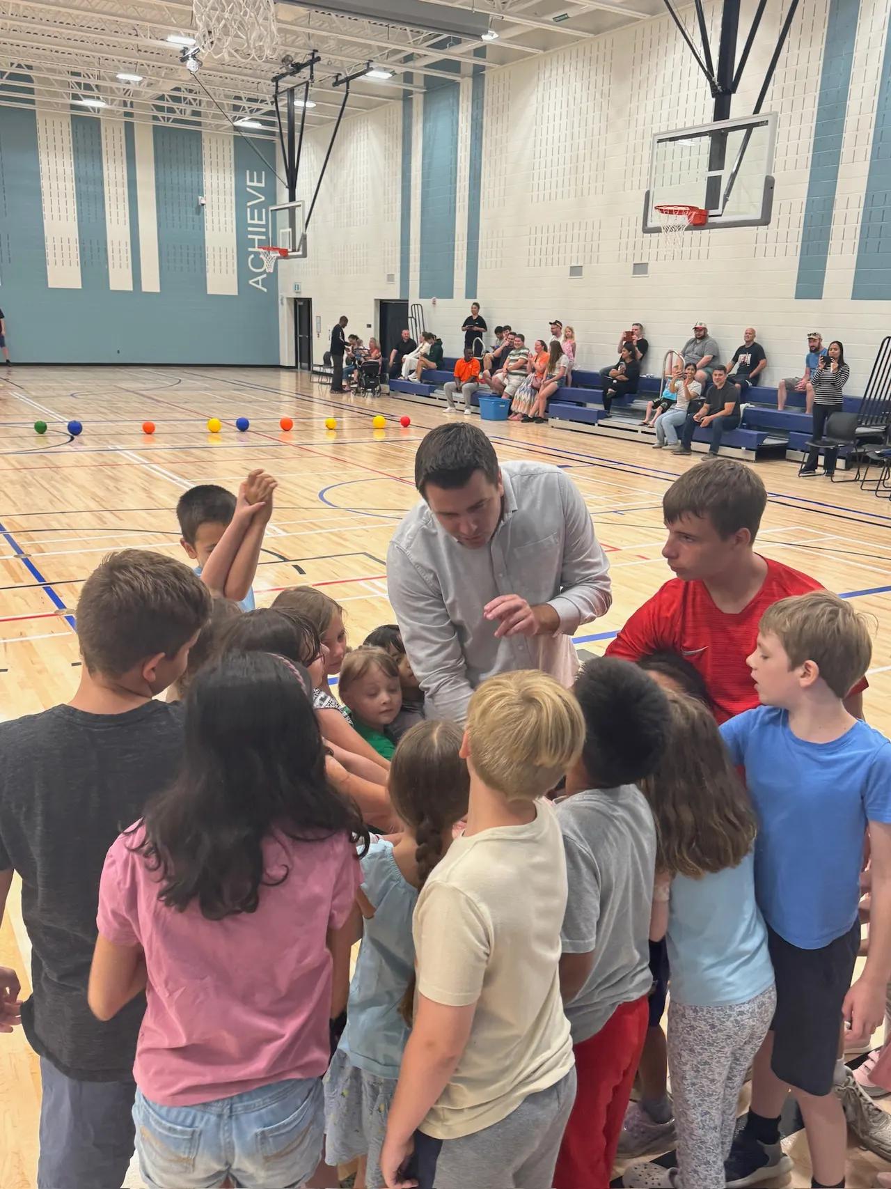 Students gathered around Matt Francis in a school gymnasium